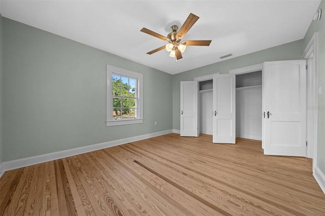 unfurnished bedroom featuring light wood-type flooring, baseboards, multiple closets, and ceiling fan