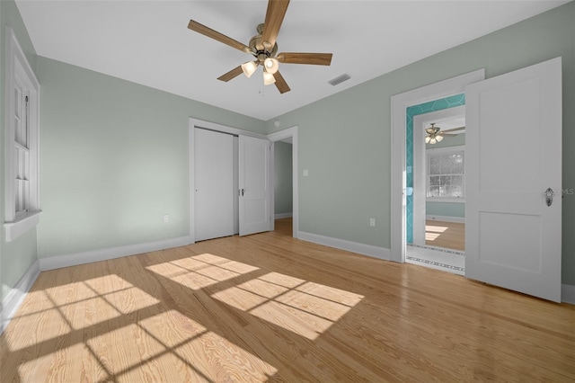 unfurnished bedroom featuring wood finished floors, baseboards, a closet, and ceiling fan
