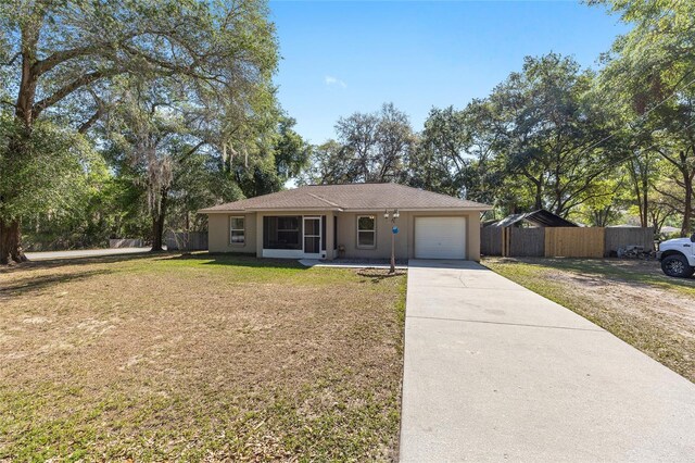 5855 SE 158th Ct, Ocklawaha, FL 32179 - ranch-style home with a front lawn, concrete driveway, fence, an attached garage, and stucco siding