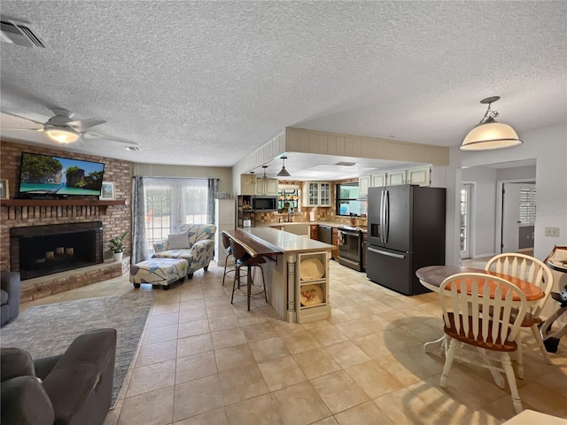 4085 SE 23rd Ter, Ocala, FL 34480 - living room featuring a ceiling fan, a textured ceiling, a fireplace, and light tile patterned floors