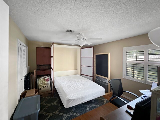4085 SE 23rd Ter, Ocala, FL 34480 - bedroom featuring wood finished floors, a closet, a desk, a textured ceiling, and a ceiling fan