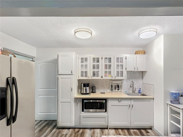 4085 SE 23rd Ter, Ocala, FL 34480 - kitchen featuring freestanding refrigerator, stainless steel microwave, light wood-style flooring, glass insert cabinets, and light countertops