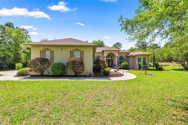 mediterranean / spanish home featuring a front lawn and stucco siding