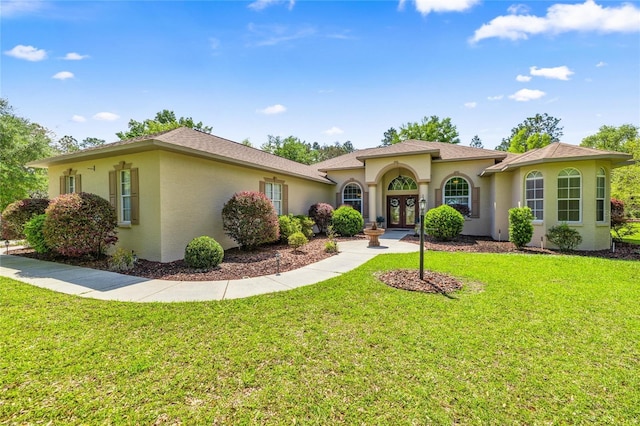 mediterranean / spanish house featuring stucco siding, french doors, and a front lawn