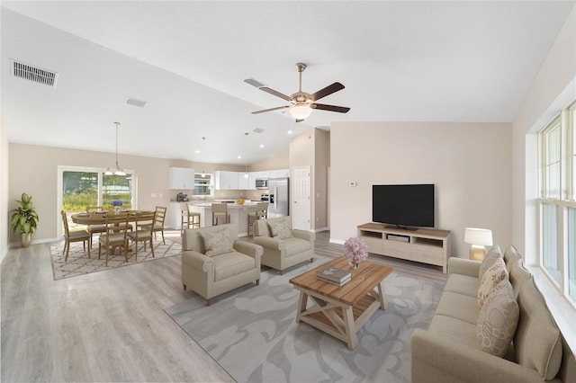 living room with lofted ceiling, light wood-type flooring, baseboards, visible vents, and ceiling fan