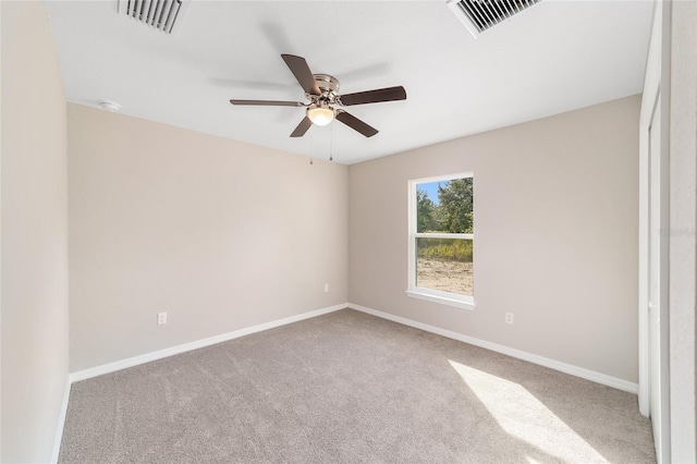 carpeted spare room with baseboards, a ceiling fan, and visible vents
