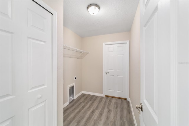 washroom featuring baseboards, light wood-style floors, laundry area, a textured ceiling, and electric dryer hookup