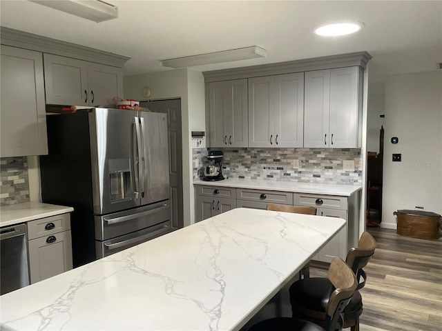 8533 SW 93rd Pl Unit A, Ocala, FL 34481 - kitchen featuring stainless steel appliances, gray cabinetry, backsplash, light stone countertops, and wood finished floors