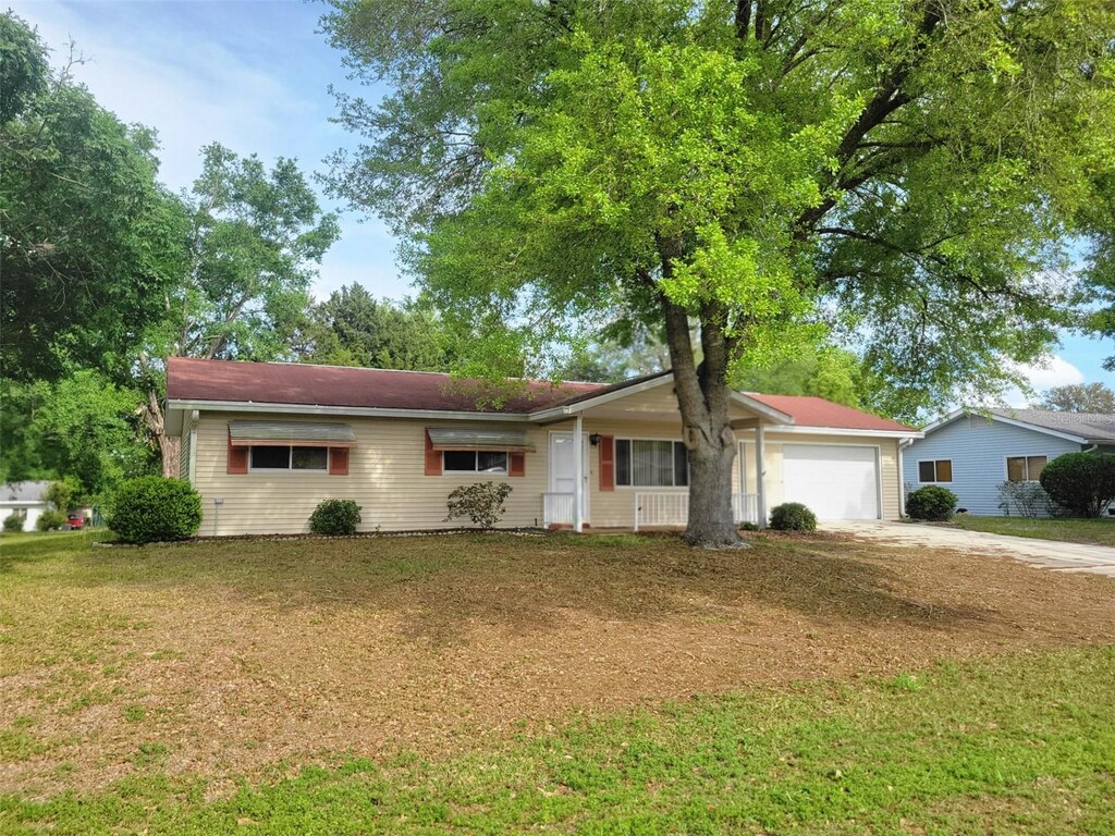 ranch-style home with a front yard, a garage, and concrete driveway