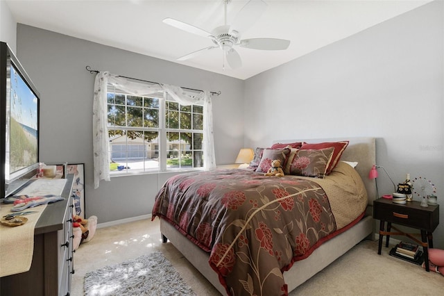 bedroom featuring light colored carpet, baseboards, and a ceiling fan