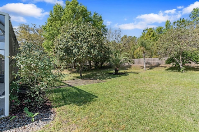 view of yard with fence and glass enclosure
