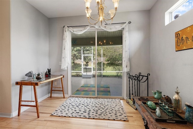 entryway with a chandelier, light wood-style floors, and baseboards