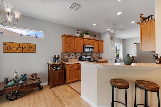 kitchen with brown cabinets, light countertops, visible vents, and stainless steel appliances