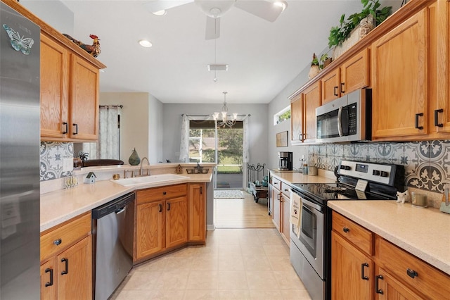 kitchen with tasteful backsplash, a peninsula, light countertops, appliances with stainless steel finishes, and a sink