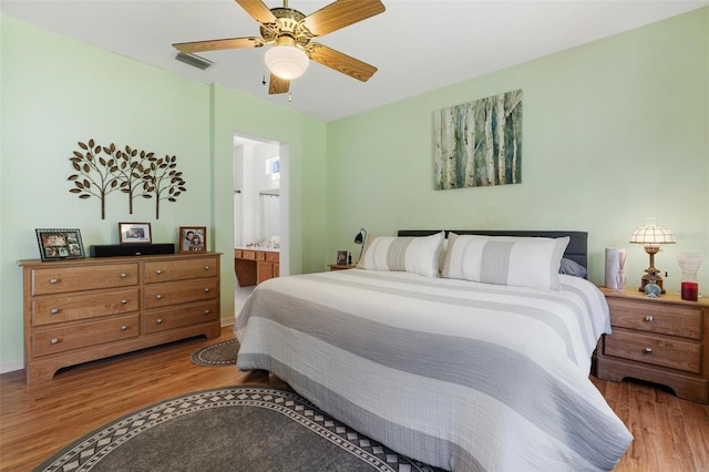 bedroom with visible vents, baseboards, ensuite bathroom, a ceiling fan, and wood finished floors