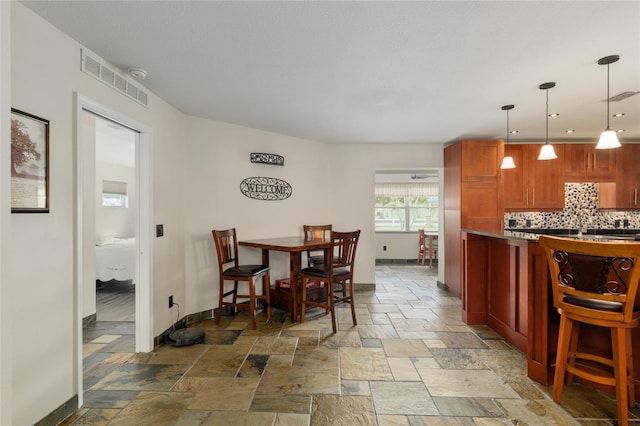 dining room featuring visible vents, baseboards, and stone tile floors
