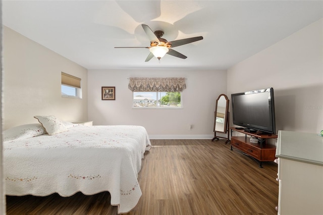 bedroom with a ceiling fan, wood finished floors, baseboards, and multiple windows