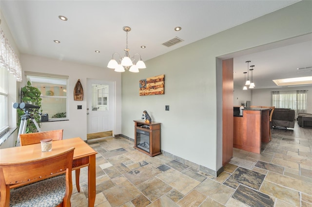 dining area featuring a chandelier, stone tile floors, baseboards, and visible vents