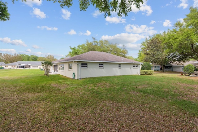 back of house featuring a lawn and stucco siding