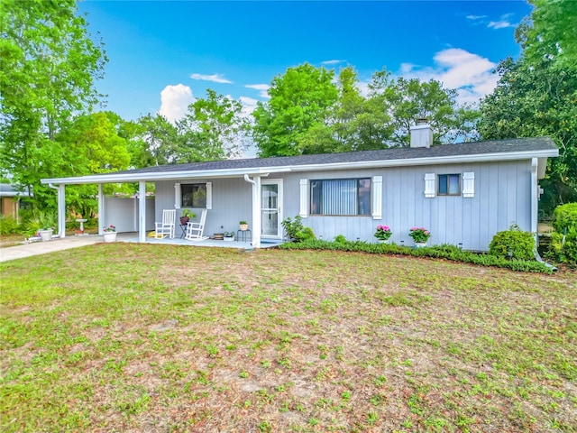single story home with covered porch, a carport, a front lawn, a chimney, and driveway