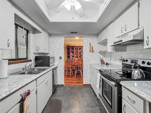 kitchen with white cabinetry, under cabinet range hood, light countertops, a sink, and stainless steel appliances
