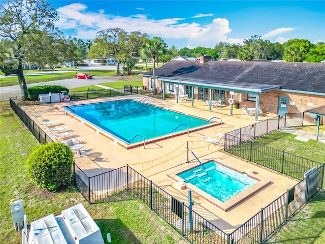 pool with a patio area, a yard, fence, and a hot tub