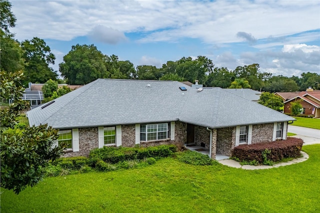 ranch-style house with brick siding, a front yard, and a shingled roof