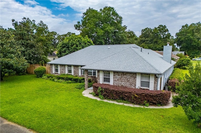 single story home featuring roof with shingles, brick siding, fence, and a front lawn