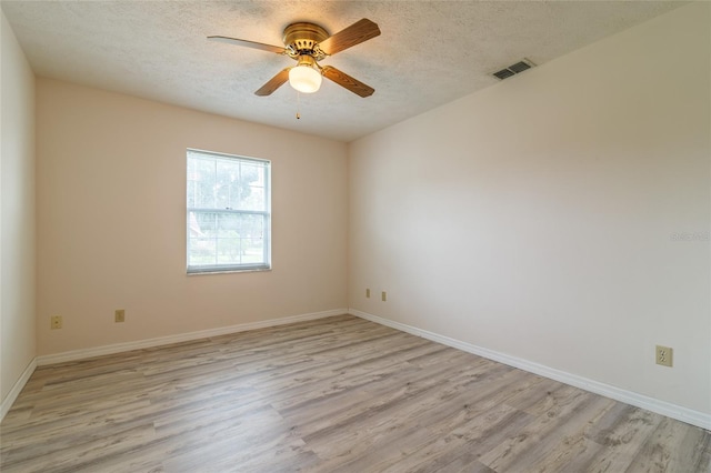 empty room with a textured ceiling, visible vents, light wood-style floors, and a ceiling fan
