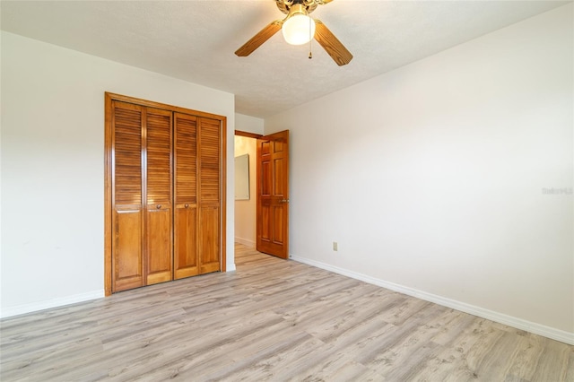 unfurnished bedroom with light wood-type flooring, baseboards, a textured ceiling, ceiling fan, and a closet