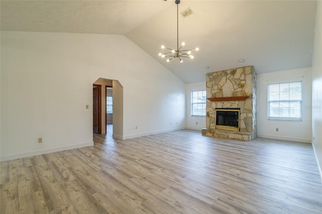 unfurnished living room featuring an inviting chandelier, arched walkways, visible vents, light wood-style flooring, and a fireplace