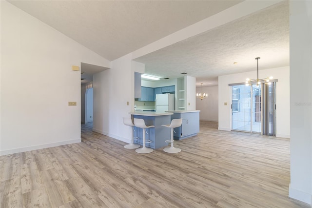 unfurnished living room with an inviting chandelier, baseboards, light wood-style floors, and a textured ceiling