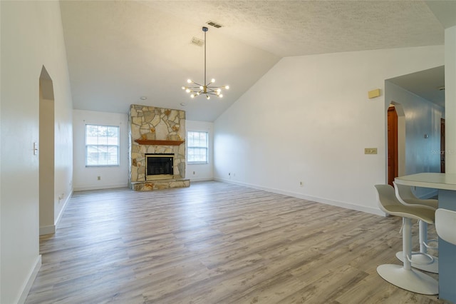 unfurnished living room featuring arched walkways, a textured ceiling, wood finished floors, and a chandelier