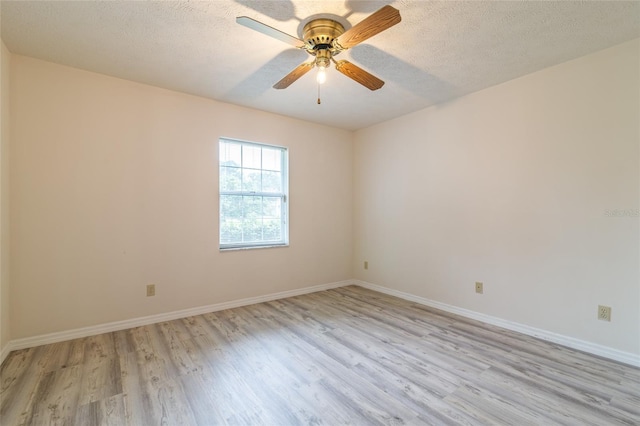 spare room featuring baseboards, light wood-style floors, ceiling fan, and a textured ceiling