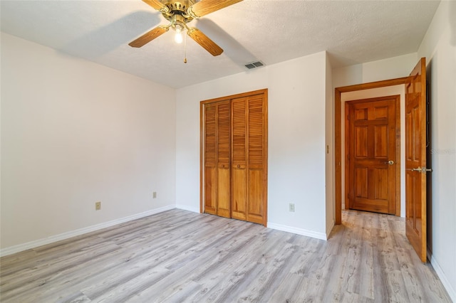 unfurnished bedroom with a closet, baseboards, light wood-style flooring, and visible vents