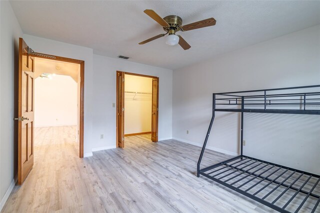 unfurnished bedroom featuring a closet, visible vents, light wood finished floors, baseboards, and a ceiling fan