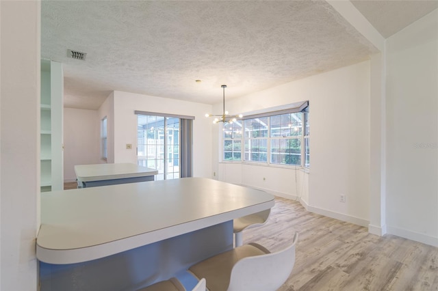 dining area featuring a textured ceiling, visible vents, a notable chandelier, and light wood finished floors