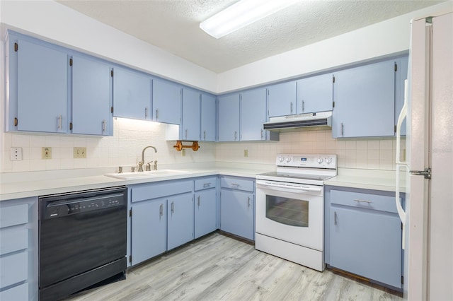 kitchen featuring tasteful backsplash, light wood-type flooring, white appliances, under cabinet range hood, and a sink