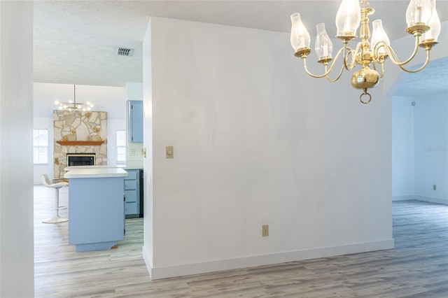 unfurnished dining area with a textured ceiling, visible vents, baseboards, light wood-type flooring, and a notable chandelier