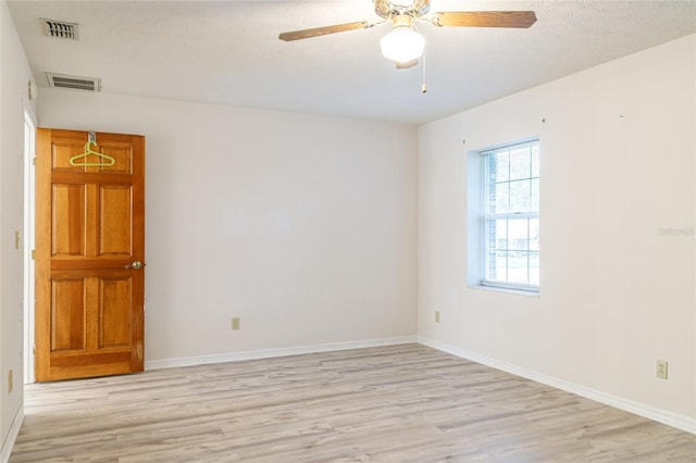 empty room featuring light wood-type flooring, baseboards, ceiling fan, and visible vents