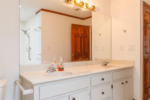 bathroom with double vanity, a sink, toilet, and crown molding