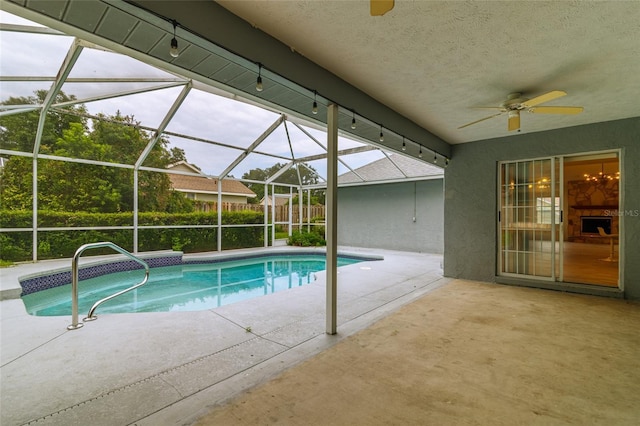 outdoor pool featuring glass enclosure, ceiling fan, and a patio area