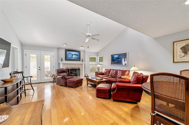 living area with a fireplace, ceiling fan, vaulted ceiling, and light wood-type flooring