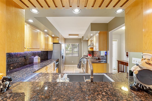 kitchen with tasteful backsplash, recessed lighting, stainless steel fridge with ice dispenser, dark stone counters, and a sink