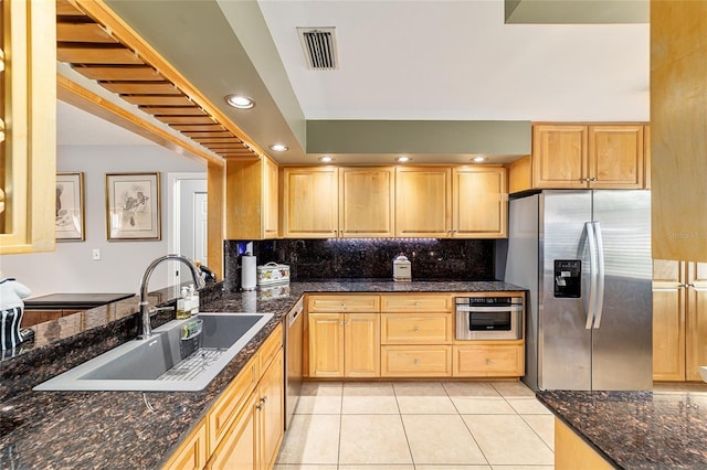 kitchen with tasteful backsplash, stainless steel appliances, light brown cabinetry, a sink, and light tile patterned flooring
