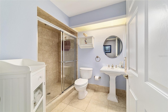 bathroom featuring baseboards, toilet, a stall shower, and tile patterned flooring