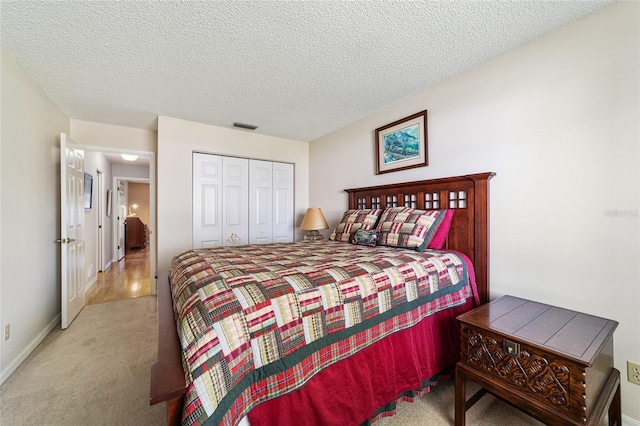 carpeted bedroom featuring a textured ceiling, a closet, and visible vents