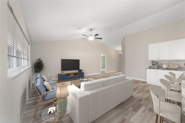 living room featuring visible vents, light wood finished floors, baseboards, a ceiling fan, and lofted ceiling