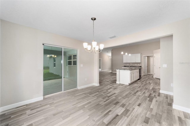 interior space featuring visible vents, baseboards, a sink, light wood-style floors, and a notable chandelier
