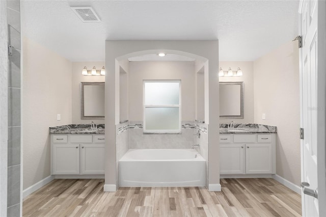full bathroom featuring a sink, visible vents, a garden tub, and wood finished floors
